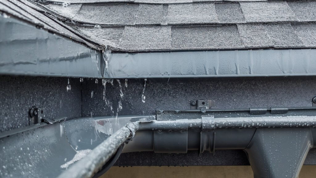 Jets of rain drain into the drainage system on the roof of the house.