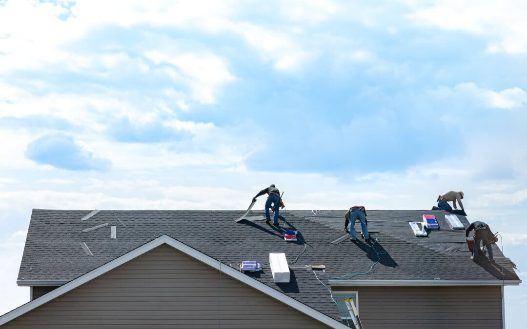 4 construction workers fixing roof against clouds blue sky, install shingles at the top of the house. Renovate, improvement, build home exterior by professional teamwork. Safety and protection concept