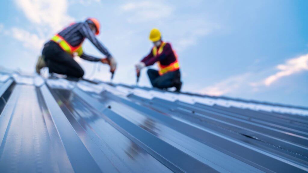 Roofers working on installing a metal roof 